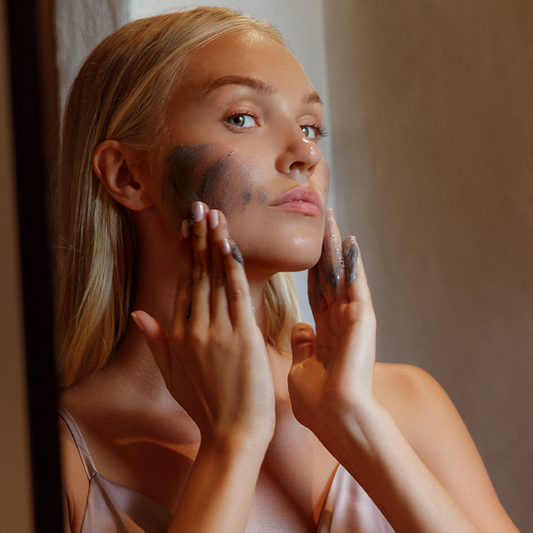 Een vrouw brengt de Marc Inbane Black Exfoliator gezichtscrub aan voor een stralende huid.